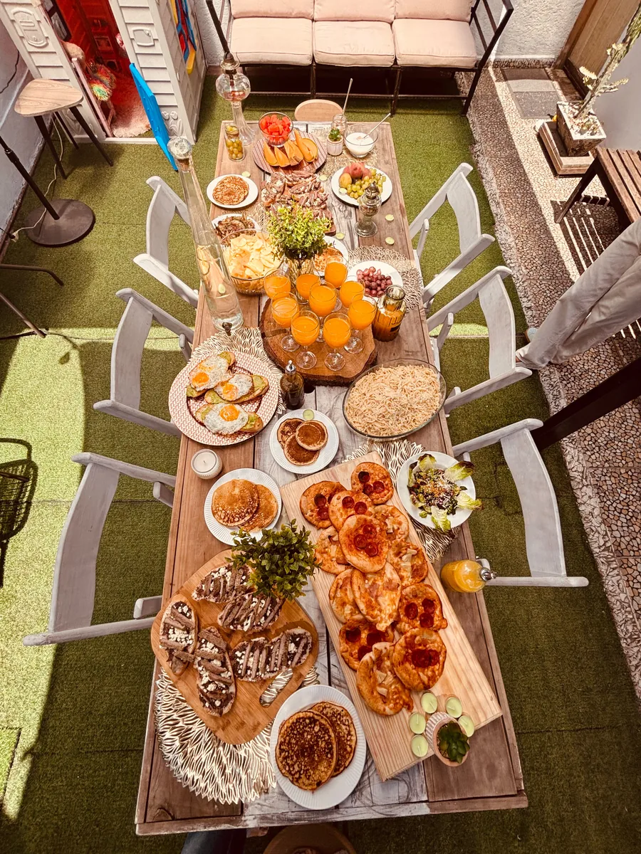 Mesa de brunch montada con huevos, pan, jugos y fruta